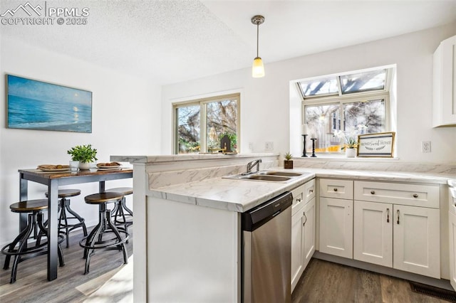 kitchen with decorative light fixtures, stainless steel dishwasher, white cabinets, light stone counters, and sink