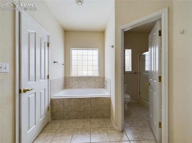 bathroom featuring tile patterned flooring, a relaxing tiled tub, and toilet