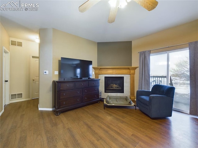 living room with a tiled fireplace, hardwood / wood-style floors, and ceiling fan