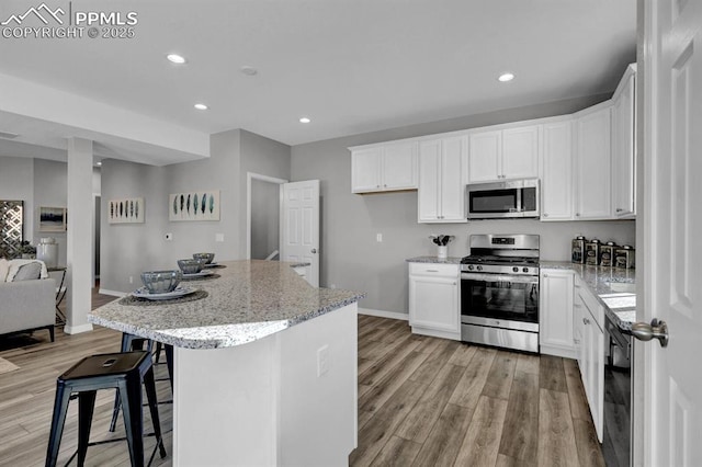 kitchen featuring light stone countertops, white cabinetry, a center island, and stainless steel appliances