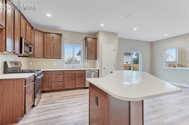 kitchen featuring a center island, a healthy amount of sunlight, stainless steel appliances, and light hardwood / wood-style flooring