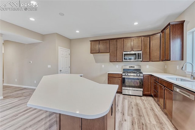 kitchen featuring appliances with stainless steel finishes, light hardwood / wood-style floors, a kitchen island, and sink