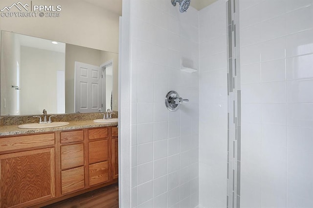 bathroom with hardwood / wood-style flooring, vanity, and tiled shower