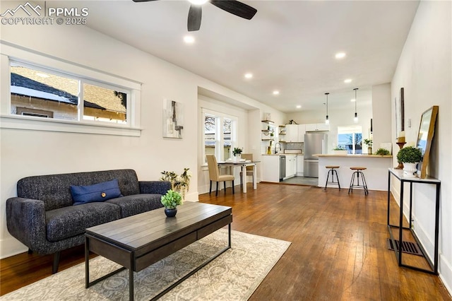 living room with dark wood-type flooring, ceiling fan, a wealth of natural light, and sink