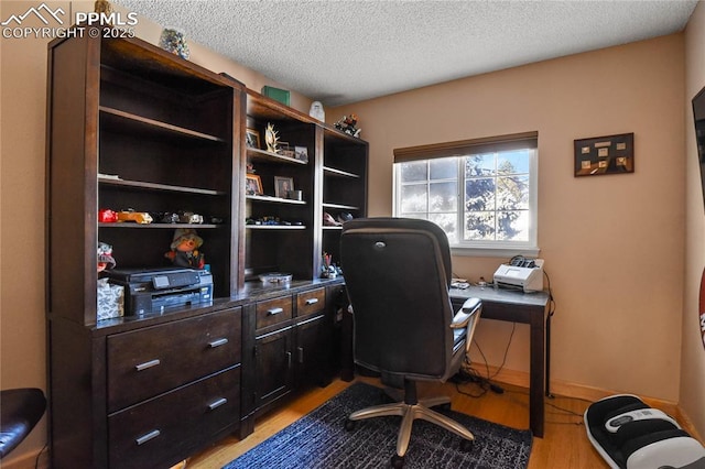 home office with a textured ceiling and light hardwood / wood-style floors