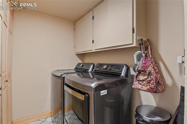 clothes washing area with light tile patterned floors, cabinets, and washer and clothes dryer