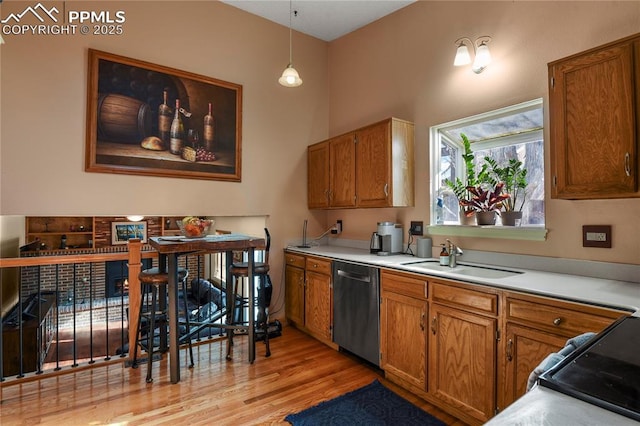 kitchen with decorative light fixtures, sink, dishwasher, and light hardwood / wood-style flooring