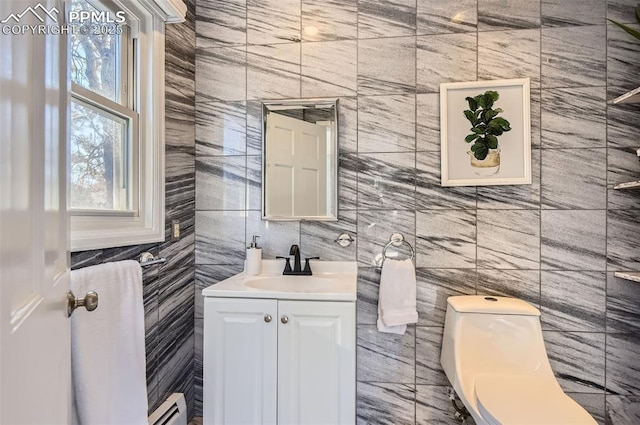 bathroom with a baseboard heating unit, tile walls, toilet, and vanity