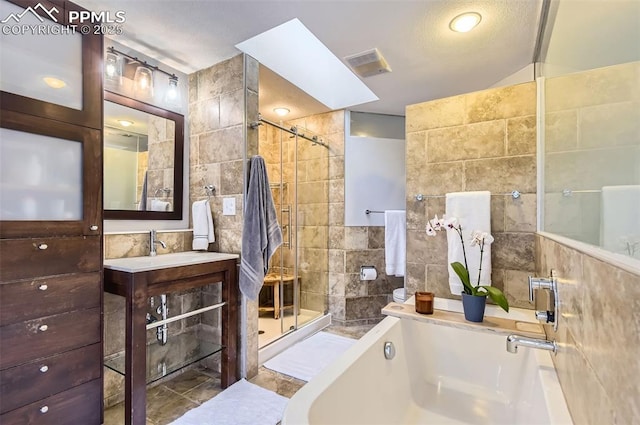 bathroom featuring vanity, tile walls, a skylight, and shower with separate bathtub