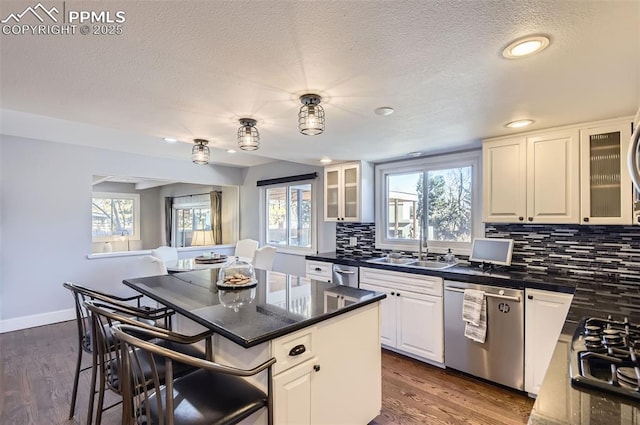 kitchen with backsplash, white cabinetry, dishwasher, and a center island