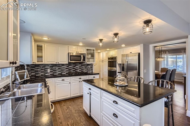 kitchen featuring dark hardwood / wood-style floors, a center island, white cabinetry, appliances with stainless steel finishes, and a kitchen breakfast bar