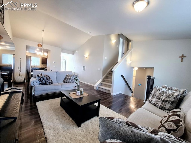 living room featuring a notable chandelier, dark wood-type flooring, and vaulted ceiling