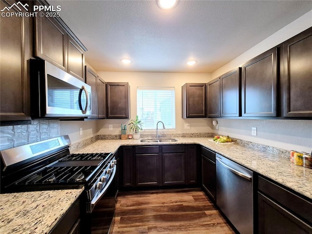 kitchen featuring stainless steel appliances, light stone countertops, sink, and dark hardwood / wood-style flooring