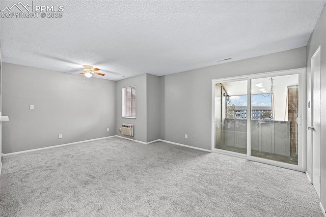 carpeted empty room with a textured ceiling, a wall unit AC, and ceiling fan