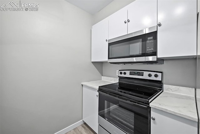 kitchen featuring light stone countertops, white cabinetry, stainless steel appliances, and light hardwood / wood-style floors