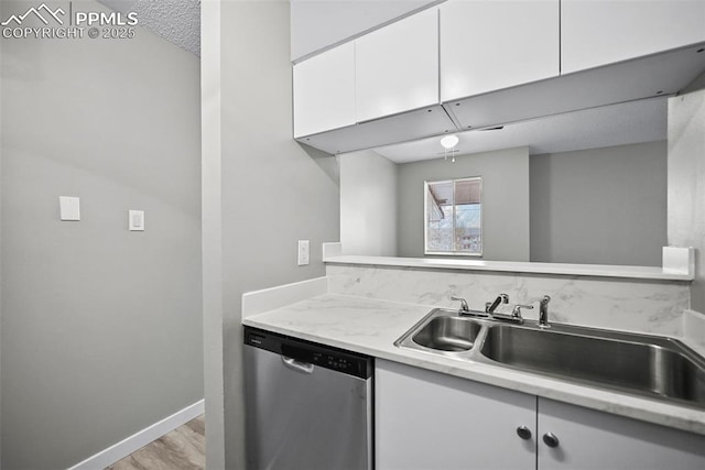 kitchen featuring sink, white cabinets, stainless steel dishwasher, and a textured ceiling