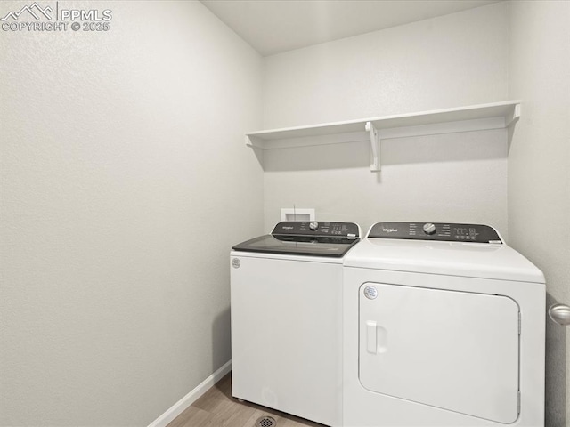 washroom featuring washing machine and clothes dryer and light hardwood / wood-style floors