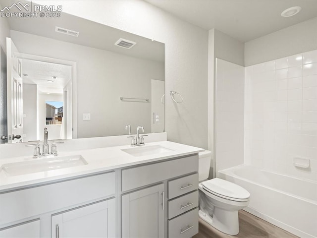 full bathroom featuring vanity, wood-type flooring, washtub / shower combination, and toilet