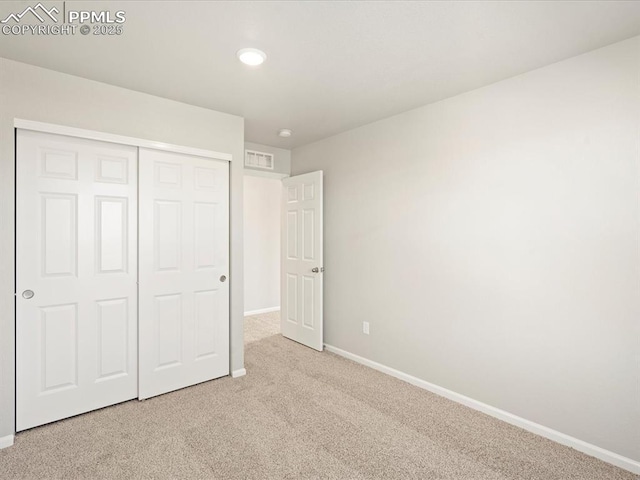 unfurnished bedroom featuring light carpet and a closet