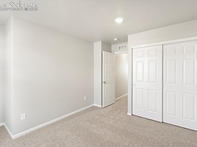 unfurnished bedroom featuring light colored carpet and a closet