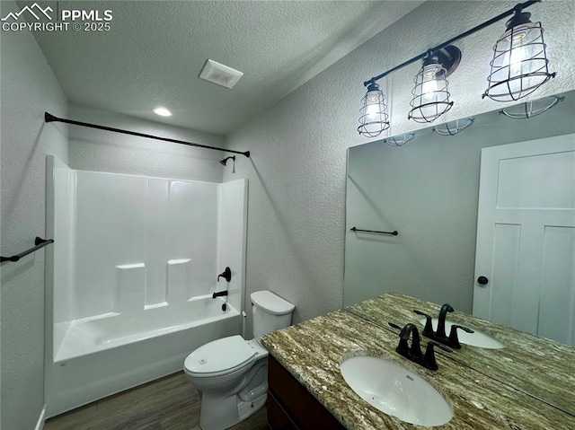 full bathroom featuring toilet, wood-type flooring, vanity, a textured ceiling, and shower / bathing tub combination