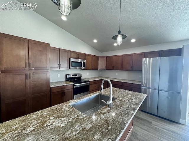 kitchen featuring hanging light fixtures, lofted ceiling, appliances with stainless steel finishes, dark brown cabinets, and sink