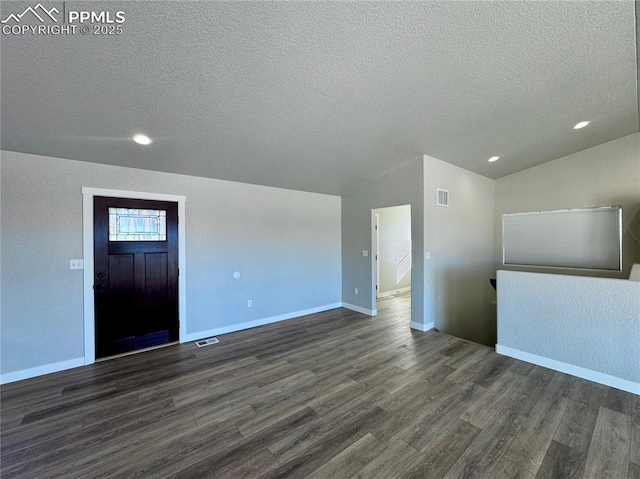 unfurnished living room with a textured ceiling, vaulted ceiling, and dark hardwood / wood-style flooring