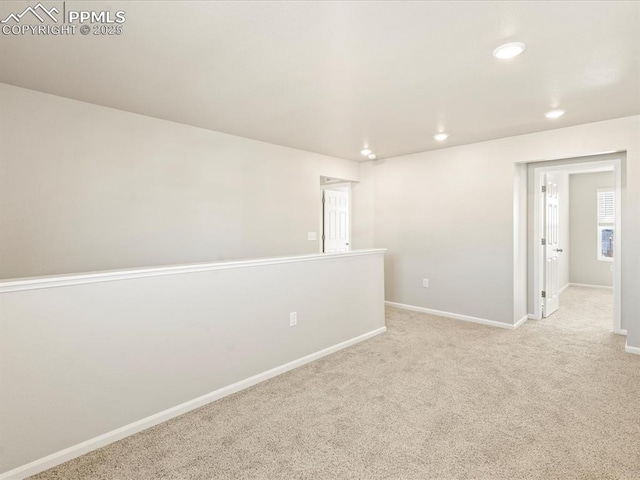 spare room featuring recessed lighting, light colored carpet, and baseboards