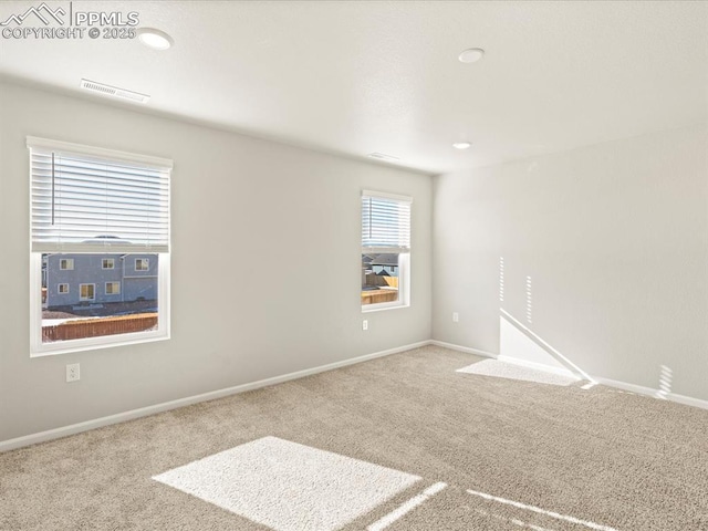 empty room with light colored carpet, visible vents, and baseboards