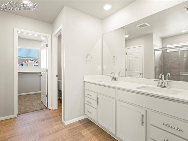 bathroom featuring wood finished floors, a sink, toilet, and double vanity