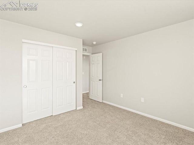 unfurnished bedroom with light carpet, visible vents, baseboards, and a closet