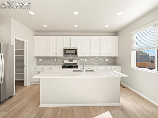 kitchen featuring an island with sink, appliances with stainless steel finishes, light countertops, and white cabinets