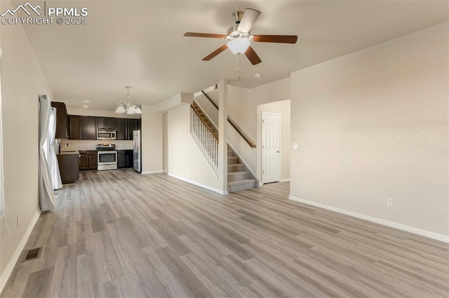 unfurnished living room with sink, light wood-type flooring, and ceiling fan with notable chandelier