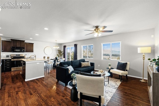 living room featuring dark hardwood / wood-style flooring, sink, and ceiling fan with notable chandelier