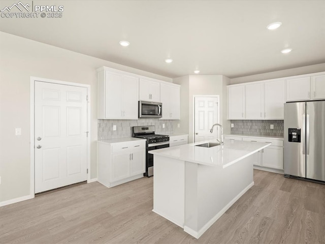 kitchen featuring sink, white cabinets, stainless steel appliances, and an island with sink