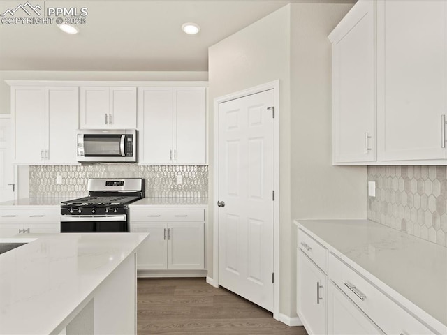 kitchen featuring light stone counters, white cabinets, dark hardwood / wood-style flooring, and stainless steel appliances