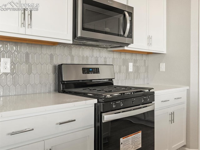 kitchen featuring stainless steel appliances, backsplash, and white cabinets