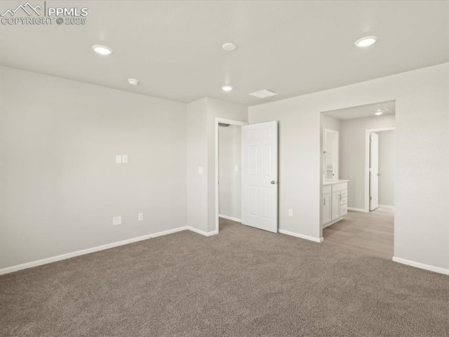 unfurnished bedroom featuring light carpet and connected bathroom