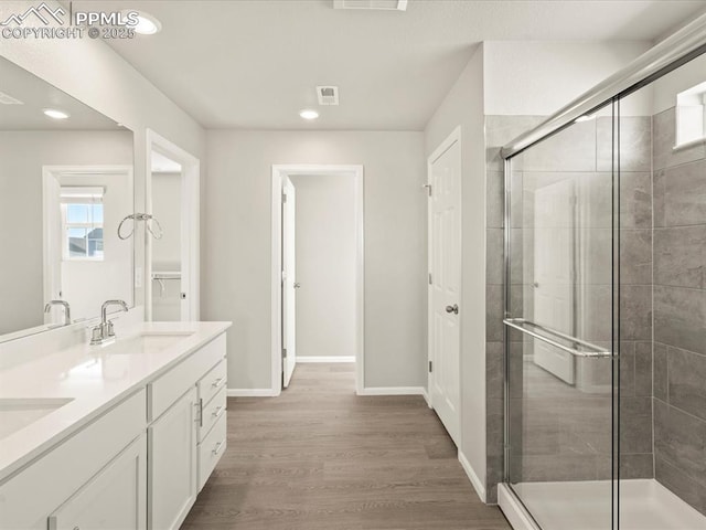 bathroom with hardwood / wood-style flooring, walk in shower, and vanity