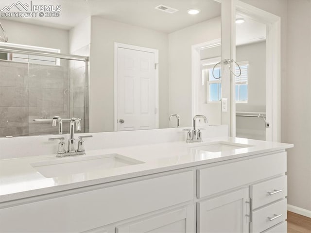 bathroom with walk in shower, vanity, and hardwood / wood-style floors