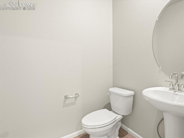 bathroom featuring toilet, sink, and hardwood / wood-style flooring