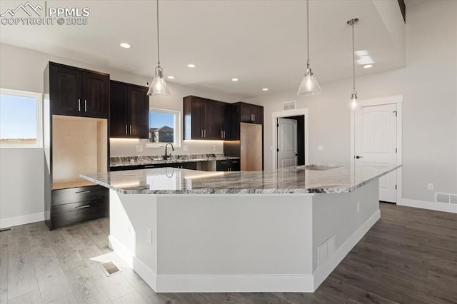 kitchen featuring decorative light fixtures, a wealth of natural light, dark brown cabinetry, and a spacious island