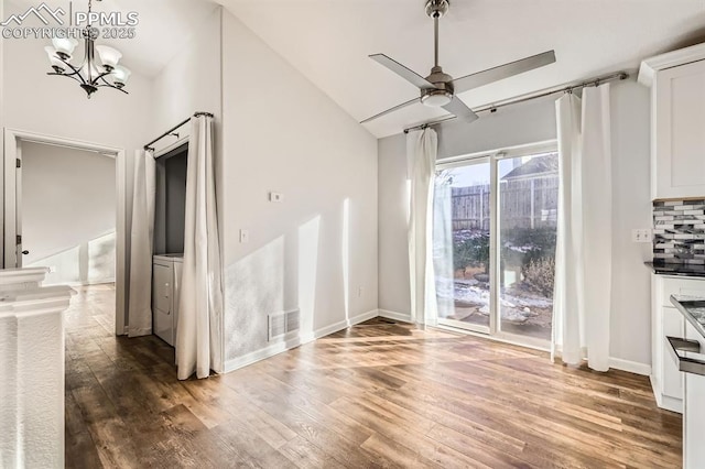 unfurnished living room with lofted ceiling, ceiling fan with notable chandelier, and dark hardwood / wood-style flooring