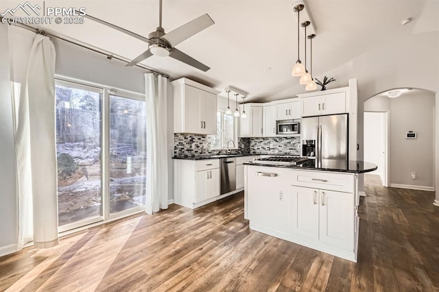 kitchen with pendant lighting, appliances with stainless steel finishes, white cabinetry, a kitchen island, and vaulted ceiling