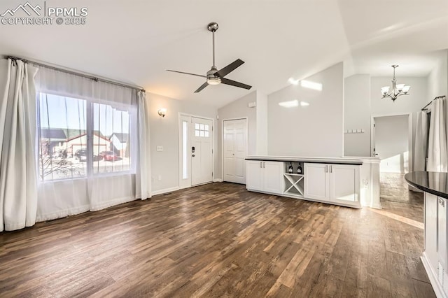 unfurnished living room featuring lofted ceiling, ceiling fan with notable chandelier, and dark hardwood / wood-style flooring