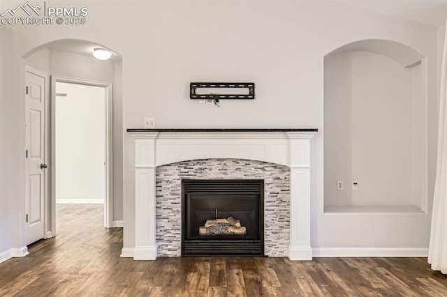 interior details featuring wood-type flooring and a tiled fireplace