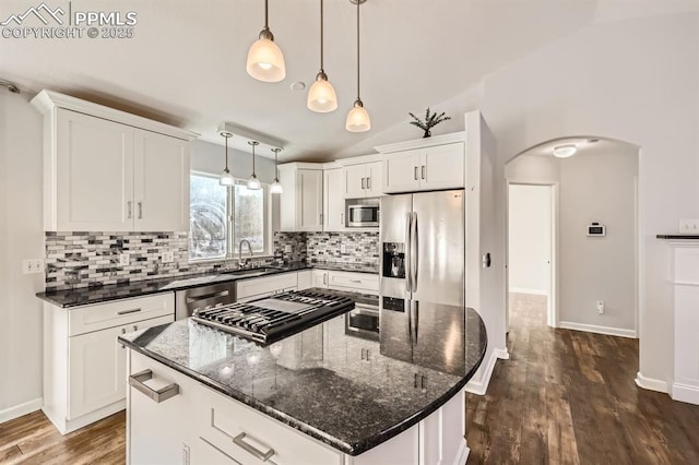 kitchen featuring white cabinetry, hanging light fixtures, stainless steel appliances, a kitchen island, and vaulted ceiling