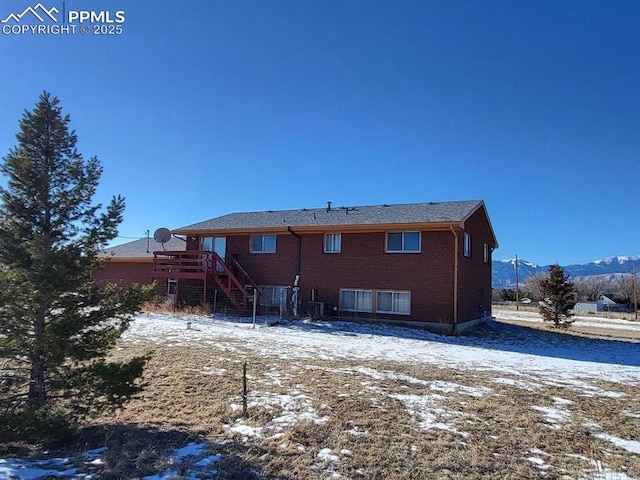 snow covered back of property featuring cooling unit and a mountain view