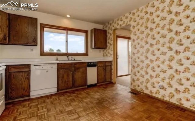 kitchen with sink, dishwasher, and dark parquet floors