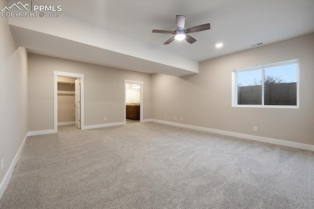 unfurnished bedroom featuring ensuite bathroom, a spacious closet, light carpet, and ceiling fan